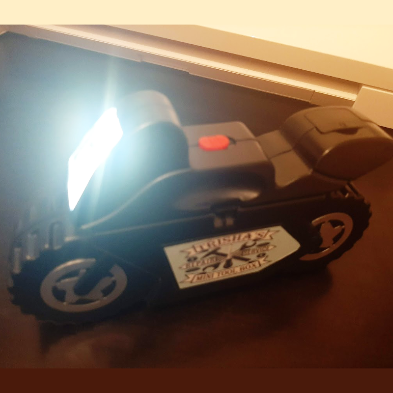 motorcycle shaped tool box with the torch on in a dark environment
